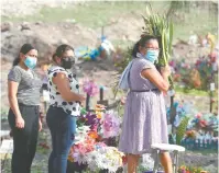  ??  ?? Varias personas visitan un cementerio, durante el Día de la Madre, en Tegucigalp­a, Honduras.