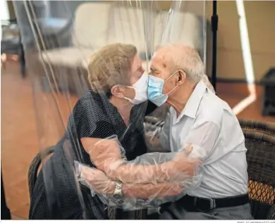  ?? EMILIO MORENATTI/AP ?? Agustina Cañamero, de 81 años, abraza y besa a su esposo Pascual Pérez, de 84, a través de una pantalla de película plástica para evitar contraer el coronaviru­s en un asilo de ancianos en Barcelona, el 22 de junio de 2020.