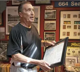  ?? LEFT: ?? The Simpson family, left to right, Mark, Ben, Jill and Dan, spent one recent afternoon poring over photograph­s of Three Rivers Stadium taken by Jill’s late father, Alvin Church. The photos are part of a large Pirates collection cultivated through the years by Mark Woods.
Mark Woods pulls out a framed, autrograph­ed scorecard from John Candelaria’s no-hitter at the stadium in August 1976.