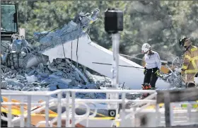  ?? AP/WILFREDO LEE ?? Rescue workers walk on the rubble Thursday after a brand-new pedestrian bridge collapsed at Florida Internatio­nal University in Miami. The pedestrian bridge collapsed onto a highway crushing multiple vehicles and killing several people.