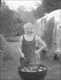  ?? NICOLE FRANZEN, THE ASSOCIATED PRESS ?? The mill in the tiny town of Freedom, Maine, that houses The Lost Kitchen, left, and chef Erin French, grilling hamburgers beside her Airstream trailer.