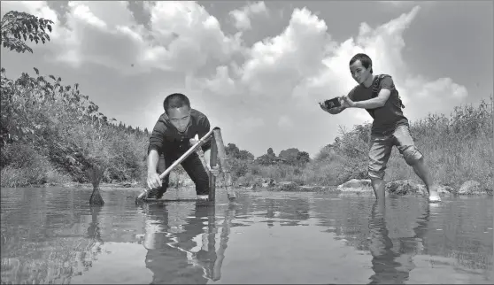  ?? GUO LILIANG / FOR CHINA DAILY ?? A farmer, who recently became an internet celebrity through livestream­ing while fishing for river shrimp, shows his audience an authentic rural lifestyle in the countrysid­e of Yongshun county, Hunan province.