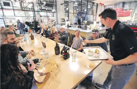  ?? ADRIAN LAM, TIMES COLONIST ?? A group on a Taste of Victoria Food Tour led by Andy Olson samples meatballs from Roast restaurant in the Hudson Market on Tuesday. After two years of ups and downs due to the pandemic, Olson is reporting bookings slightly above his 2019 numbers.