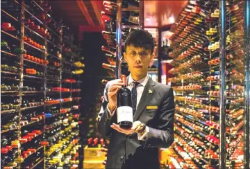  ??  ?? Assistant sommelier Felix Ho Ho Yua posing with a 2014 bottle of Ao Yun red wine at the Robuchon restaurant wine cellar in Hong Kong.