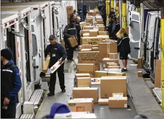  ?? ALYSSA POINTER PHOTOS / ALYSSA.POINTER@AJC.COM ?? FedEx employee belt pullers fill trucks with packages for their daily route at the FedEx shipping center Thursday in Alpharetta.