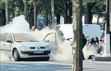  ?? NOEMIE PFISTER / AP ?? Policías franceses extinguen el fuego del coche; a la derecha, en el suelo, el autor del ataque