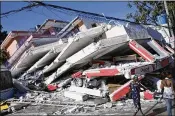  ?? LANNIS WATERS / THE PALM BEACH POST 2010 ?? Women walk past a commercial building in Petionvill­e, Haiti, leveled by a magnitude-7.0 earthquake that hit in January 2010.