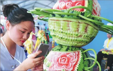  ?? WANG BIAO / FOR CHINA DAILY ?? A contestant uses her mobile phone to take a photo of a sculpture she made out of a watermelon at an innovation contest held in Fuyang, Anhui province, over the weekend.