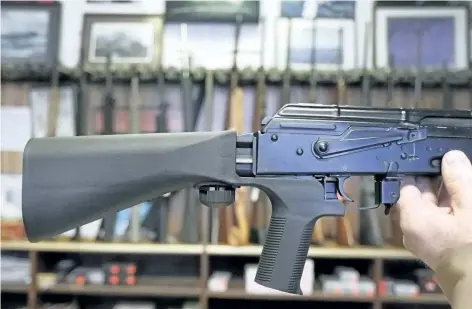  ?? GEORGE FREY/GETTY IMAGES ?? A bump stock device (left) that fits on a semi-automatic rifle to increase the firing speed, making it similar to a fully automatic rifle, is installed on a AK-47 semi-automatic rifle, (right) at a gun store in Salt Lake City, Utah. The U.S. Congress...