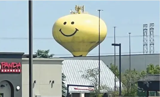  ?? PAUL EISENBERG/DAILY SOUTHTOWN PHOTOS ?? Calumet City’s Mr. Smiley water tower peers over a shopping area in the summer. It’s one of two personable water towers in the city, painted with faces in 1973, that were featured in a Landmarks column in 2023.