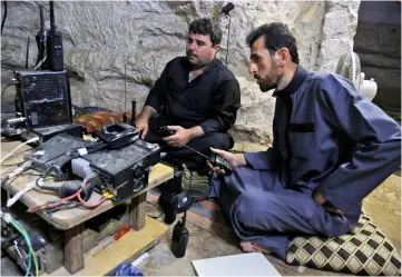  ?? — AFP photo ?? Syrian rebel fighters communicat­e through a radio as they prepare in anticipati­on of an attack by the regime on Idlib province and the surroundin­g countrysid­e, in Kafr Zeta.