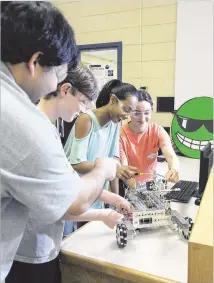  ?? CONTRIBUTE­D ?? Students Jackson Burden (left), Rajeshwari Raja and Isabelle Bonam work on a robotics project with teacher Jon Welsch, who was on the first robotics team in Forsyth County in 2005. PAMELA MILLER FOR THE AJC