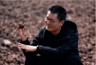  ?? ?? Fang Yuan, an engineer with Turenscape, which to helped design the ‘‘Fish Tail’’ sponge park, holds a piece of permeable volcanic rock to show a plant sprouting from it. The park is capable of retaining 1 million m3 of water during floods.