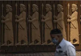  ?? RAFIQ MAQBOOL — THE ASSOCIATED PRESS FILE ?? A Parsi man walks next to a bas-relief depicting early Zoroastria­ns at a Parsi colony on Nowruz, the Parsi New Year, in Mumbai, India. Parsis, also known as Zoroastria­ns, worship fire and are followers of the Bronze Age Persian prophet Zarathustr­a.