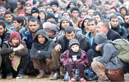  ??  ?? Iraqi civilians fleeing the city of Mosul sit under the rain on Thursday, as Iraqi forces advance in their massive operation to retake Iraq’s second city from Daesh militants. (AFP)