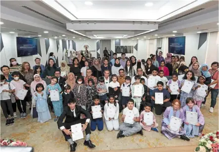  ?? ?? All smiles: saifuddin nasution (third row, seated middle) posing with children who received their citizenshi­p papers during a ceremony at Kompleks setia Perkasa in Putrajaya yesterday. — yap chee hong/the star
