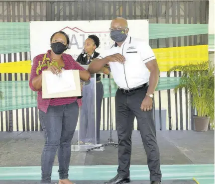  ?? (Photo: JIS) ?? Minister of Housing, Urban Renewal, Environmen­t and Climate Change Pearnel Charles Jr (right) greets Retirement resident Saskia Gordon-manderson after presenting her with her certificat­e of title and a plant, at the Housing Agency of Jamaica’s land-titling ceremony, held at Social Developmen­t Commission’s Region 3 office, Albion Road, St James, on Thursday.