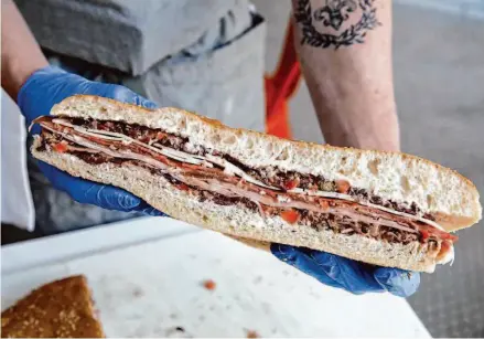  ?? Photos by Juliana Yamada/The Chronicle ?? Peterson Harter crafts his muffuletta to make each bite the same as the first. “I feel like it’s about to have its moment,” Harter said.