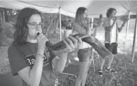  ?? AP ?? Robin Asch, from left, Ava Katz and Noah Katz practice playing their shofars, the ancient musical horns used in Judaism, under a tent set upon outside Temple Beth El, in Augusta, Maine. The recent COVID-19 upsurge is disrupting plans for full-fledged in-person services.