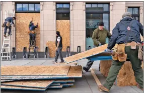  ?? (AP/Jacquelyn Martin) ?? A crew boards up a Walgreens in Washington on Friday as a precaution ahead of Election Day. The site manager said the workers were hired to put coverings on windows at several Walgreens throughout the city. Meanwhile, President Donald Trump appeared to drop plans for holding a watch party at his hotel in D.C.