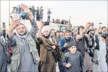  ?? ?? Spectators take videos as they watch modified cars compete in a drag race along a street in Kabul.