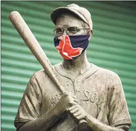  ?? Billie Weiss / Boston Red Sox / Getty Images ?? One of the “Teammates” statues at Fenway Park wears a makeshift mask on April 9.