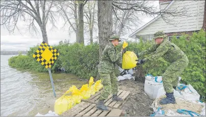  ?? CP PHOTO ?? Members of the Canadian army place sandbags next to rising floodwater­s in the Montreal borough of Pierrefond­s Sunday following flooding in the region.