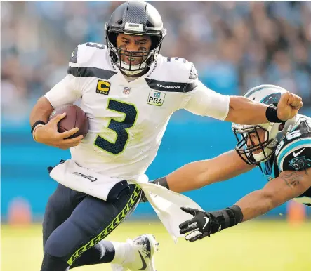  ?? GRANT HALVERSON/GETTY IMAGES ?? Seattle Seahawks quarterbac­k Russell Wilson constantly escaped pressure by Wes Horton and the rest of the Carolina Panthers Sunday in Charlotte, N.C. Wilson threw a pair of touchdowns and 339 yards in rallying the Seahawks to a 30-27 victory.