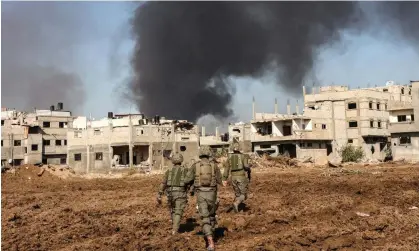  ?? Photograph: Gil Cohen-Magen/AFP/Getty Images ?? Israeli soldiers walk next to damaged buildings in the north of the Gaza Strip in a photo taken during a controlled tour on 19 December.