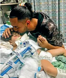  ?? AP ?? Ali Hassan kisses his dying 2-yearold son Abdullah in a Sacramento hospital. The boy’s Yemeni mother, blocked by the Trump administra­tion’s travel ban, has won her fight for a waiver that would allow her to travel to see her son.