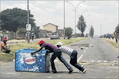  ??  ?? DAYLIGHT THEFT: Locals push a freezer after looting it from a shop, believed to be owned by a foreign national, during service delivery protests in Mohlakeng, west of Johannesbu­rg, recently. The writer says although looting seems to be common during...