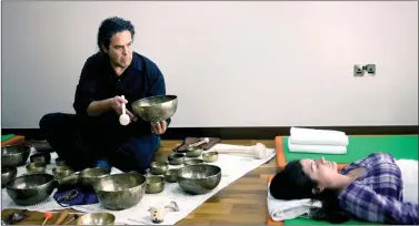  ??  ?? A wellness practition­er performing Tibetan singing bowl therapy.