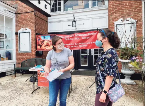  ?? Grace Duffield / Hearst Connecticu­t Media ?? Francesca DeRosa signs a petition given to her by Amy Zinser in front of the New Canaan Playhouse on Sunday that will prompt a referendum that if passed will reverse a decision on school start times.