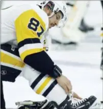  ?? TOM MIHALEK — THE ASSOCIATED PRESS ?? Penguins’ captain Sidney Crosby tightens the laces on his skates while warming up Sunday for Game 3 of a playoff series with the Flyers. Crosby collected a goal and three assists to kick the Flyers closer to the edge of eliminatio­n.