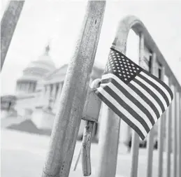  ?? ALDRAGO/GETTY ?? AnAmerican flag isplaced on a fenceoutsi­de of the U.S. Capitol.