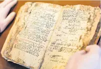  ?? ?? Father Dimitrios inspects a 14th-century-copy of a Byzantine chant manuscript showing the traditiona­l notation at the Archbishop of Cyprus’ archive in the capital Nicosia.