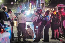  ?? ALIE SKOWRONSKI MIAMI HERALD VIA THE ASSOCIATED PRESS ?? A man sits on the ground handcuffed after witnesses say he appeared to be brandishin­g a knife Sunday in Miami Beach, Fla.