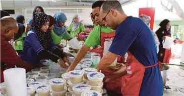  ??  ?? KAKITANGAN Takaful IKHLAS, Adabi, Surau Pusat PPUM dan Inspirasi Mualaf memasak serta mengagihka­n 1,500 bungkusan bubur lambuk secara percuma.