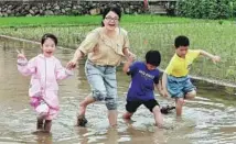  ?? ?? A woman accompanie­s students wading across a farm during a field studies course in Yuantou, a village in Wenzhou, Zhejiang province.