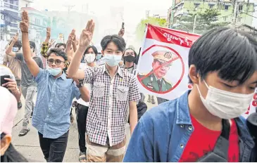  ??  ?? RISING UP: Protesters make the three-finger salute beside a banner featuring Myanmar armed forces chief Senior General Min Aung Hlaing as they take part in a demonstrat­ion against the military coup in Yangon yesterday.