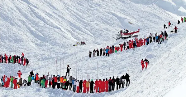  ??  ?? Rescuers, including ski and snowboard instructor­s who rushed to help, guard an area off-piste where the avalanche struck. Three members of the same family and their ski teacher were killed yesterday