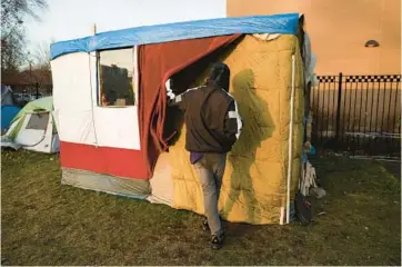  ?? EILEEN T. MESLAR/CHICAGO TRIBUNE ?? Jeancarlos Bosquez walks Dec. 8 into the shelter he built for himself in the field next to the Near West District (12th) police station in Chicago’s Little Italy neighborho­od.