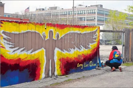  ?? SHAFKAT ANOWAR/AP PHOTO ?? Andrea Fernanda Serrano kneels Friday as she pays her respects at the site, now marked with a mural, where 13-year-old Adam Toledo was shot by police in the Little Village neighborho­od of Chicago, a day after the body camera video release of the fatal police shooting. Story,
