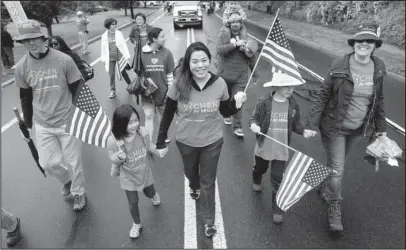  ?? The Associated Press ?? IN THE CARDS: Christine Lui Chen, center, who is running for state senate during the November elections, participat­es in the Bridgewate­r Memorial Day Parade on May 29 in Bridgewate­r, N.J. Chen, a 36-year-old health care executive in New Jersey and mother of two small children, had never considered entering politics, focusing instead on her family, her career and her community. That all changed in January, when she attended the Women’s March on Washington. Thirteen hours later, she emailed Democratic officials: “Here’s my resume. I want to get involved.”
