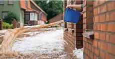  ??  ?? Eine Frau in Rhüden (Niedersach­sen) versucht, das Wasser mit einem Eimer aus ihrem Haus zu bekommen.