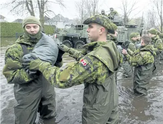  ?? RYAN REMIORZ/THE CANADIAN PRESS ?? Canadian Forces personnel unload sandbags, Monday in DeuxMontag­nes, Que.