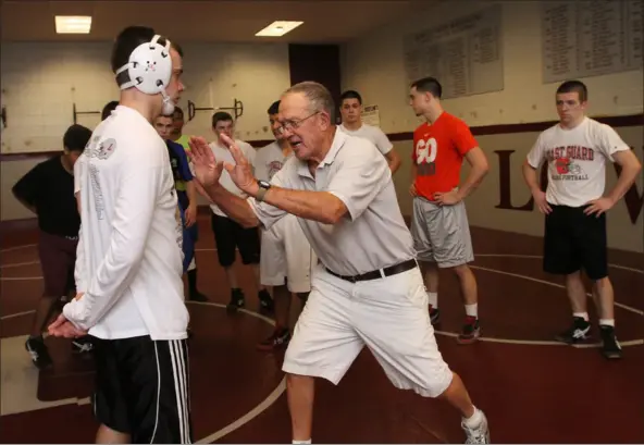  ?? JULIA MALAKIE — LOWELL SUN ?? During a Dec. 1, 2011practi­ce, Lowell High wrestling coach George Bossi demonstrat­es a drill to senior Connor Mchugh. Bossi, still coaching at age 87, has led the Red Raiders to five New England championsh­ips.