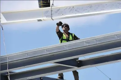  ?? Photos by Ernest A. Brown ?? A constructi­on worker guides the final steal beam into place during a topping-o ceremony at Baldwin Elementary School, presently under constructi­on and slated to open in September 2025.