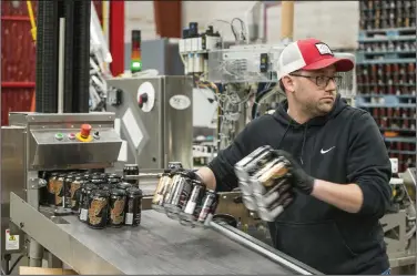  ?? (NWA Democrat-Gazette/Ben Goff) ?? Reid Walker stacks six packs of India Pale Ale as they come off the canning line earlier this month at Ozark Beer Co. in downtown
Rogers.