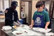  ??  ?? ABOVE: Josey Howell (from left), a sixth-grader at Model, serves up pancakes, with guidance from Optimists Jim Bojo and Bill Fron, to customer Gavin Rood.RIGHT: Jamarion Reddick (left) and Asa Holbert stuff to-go boxes.BELOW: Tables at the Civic Center stayed full most of the morning Saturday for the 58th annual Rome Optimist Pancake Breakfast./ Doug Walker